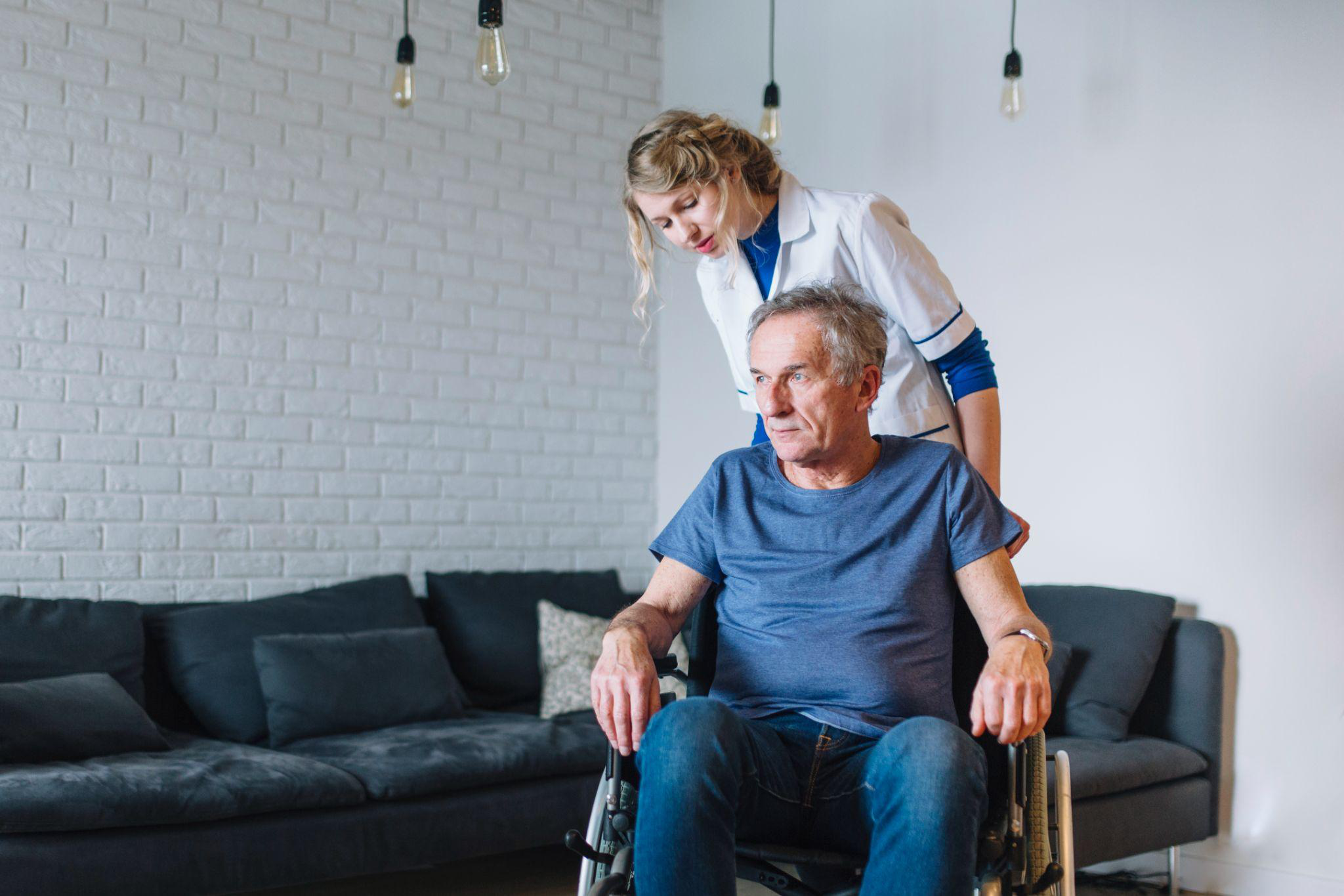 caregiver assisting a senior man in a wheelchair at home while evaluating home care provider options