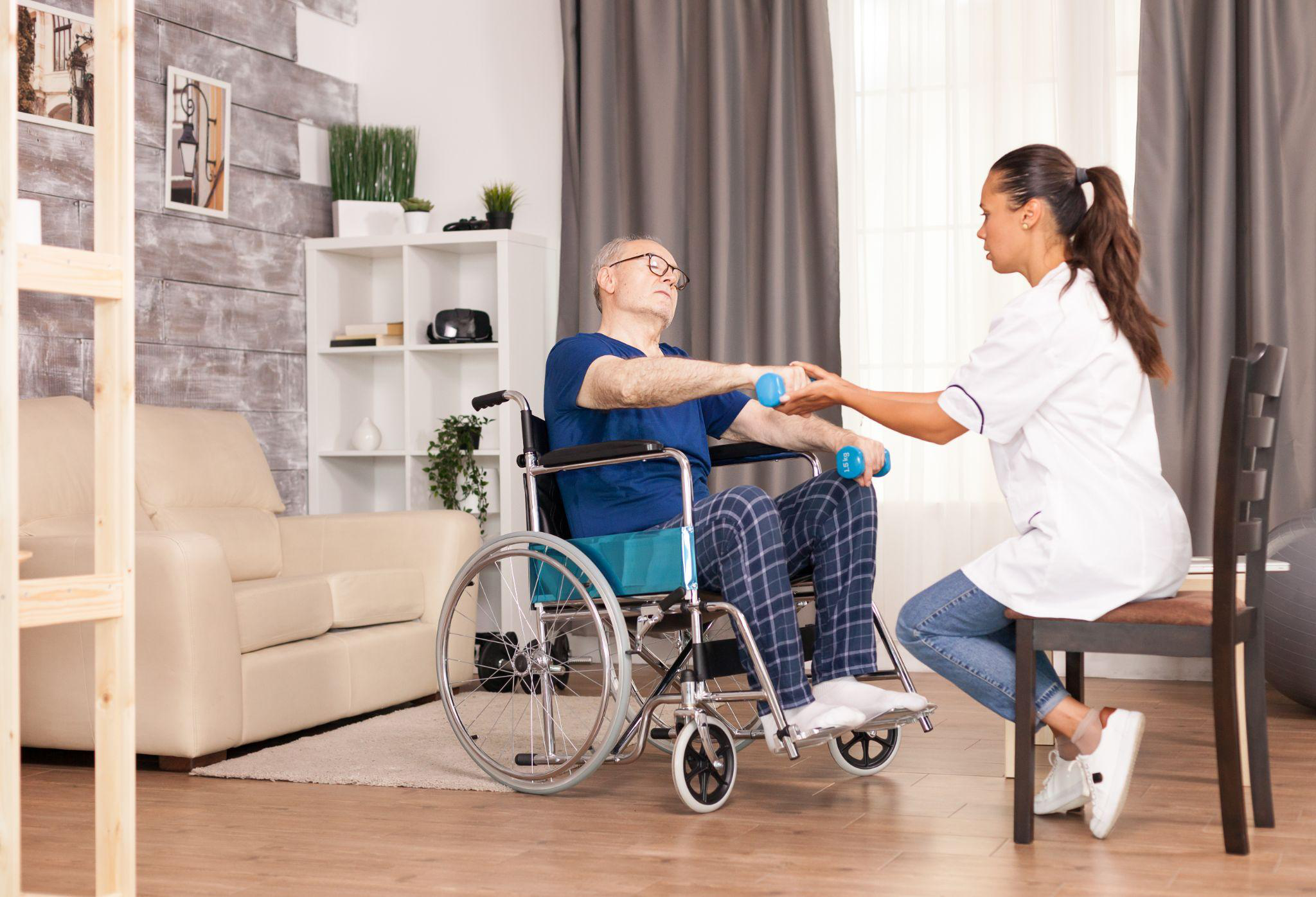 Senior doing light rehabilitation exercise with a caregiver at home
