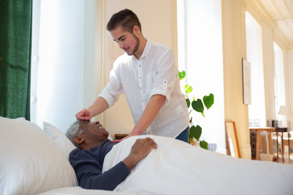 Caregiver checking on a senior resting in bed during recovery at home