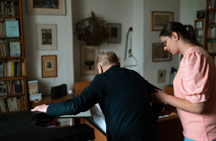 A home health aide in New Jersey guiding a senior safely with his walker.