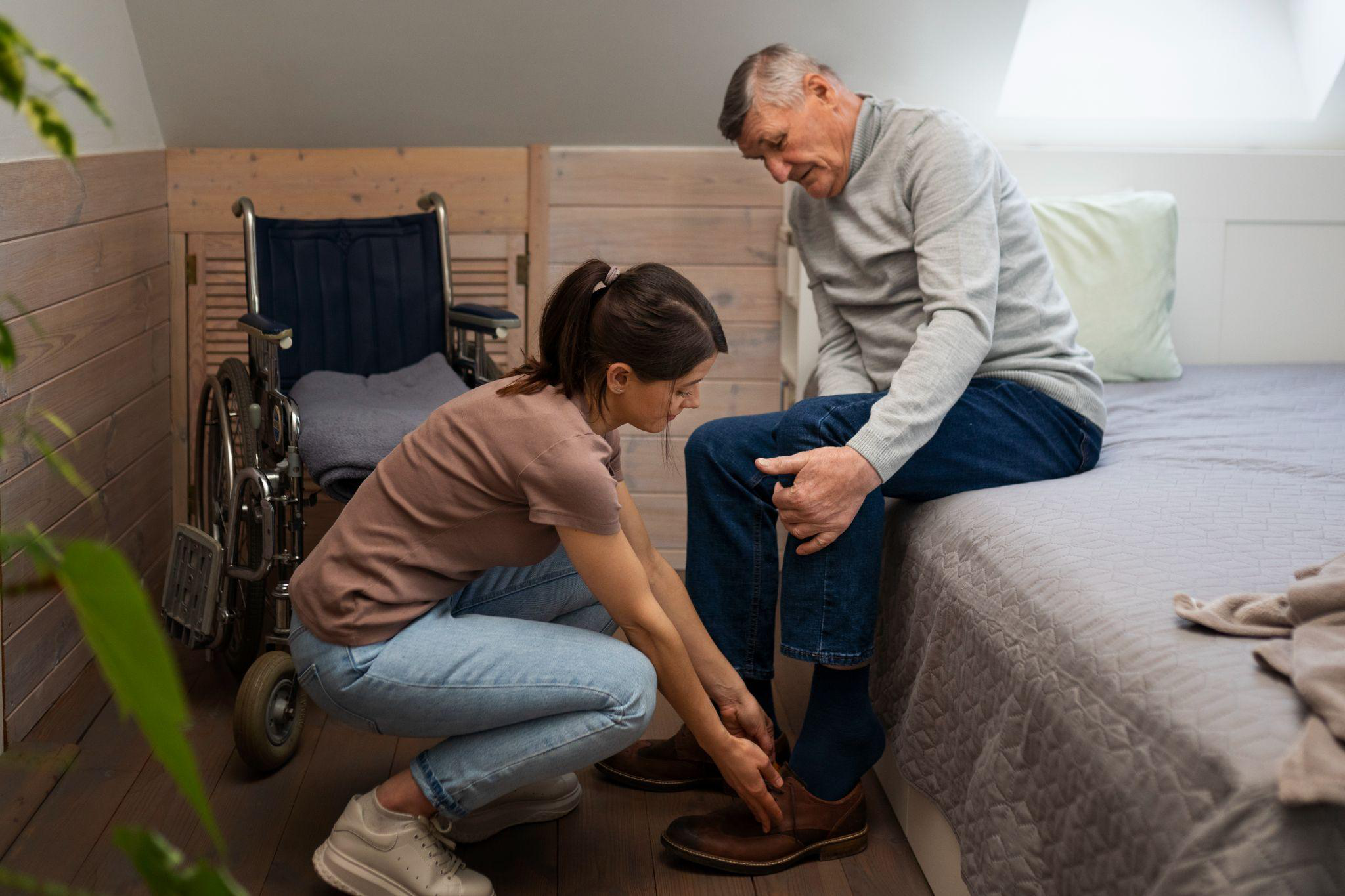 Caregiver helping an older adult with footwear at home